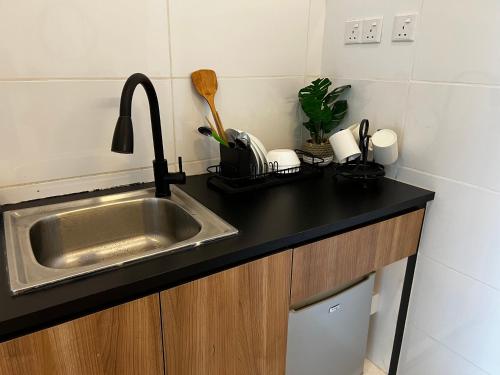 a kitchen with a sink and a black counter top at ITCC Manhattan Suites by PRIME in Penampang