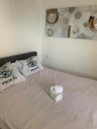 a white bed with two pillows with eyes on it at טבריה in Tiberias