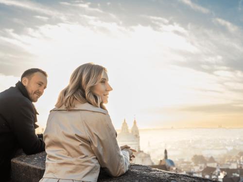 a man and a woman sitting on a ledge overlooking a city at Falkensteiner Boutique Hotel Prague in Prague