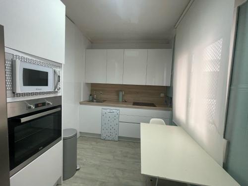 a small kitchen with white cabinets and a microwave at Catedral Plaza in Murcia