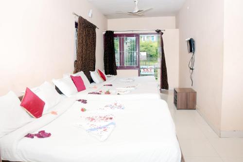 a bedroom with two beds with white sheets and red pillows at Grass dew in Yercaud