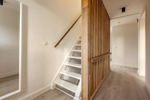 a wooden staircase in a room with a white wall at Maison Mathieu in Bilzen