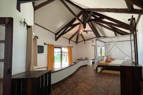 a bedroom with a bed in a room with wooden ceilings at Ravintsara Wellness Hotel in Ambaro