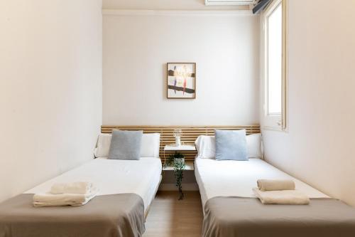 two beds in a room with white walls at Sagrada Familia III by Enjoy Apartments in Barcelona
