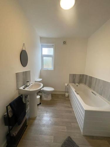 a bathroom with a tub and a toilet and a sink at Lovely 3 Bedroom property with extensive parking in Birmingham