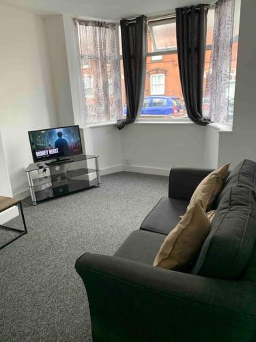 a living room with a couch and a tv at Lovely 3 Bedroom property with extensive parking in Birmingham