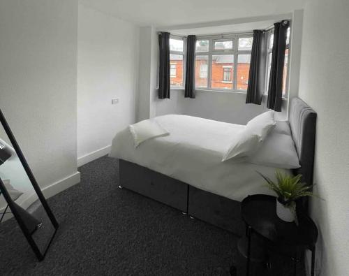 a bedroom with a white bed with a window at Lovely 3 Bedroom property with extensive parking in Birmingham