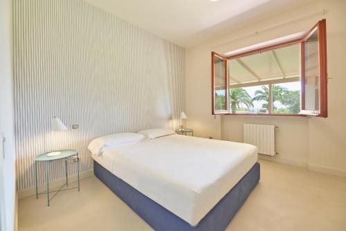 Villa Elle Exclusive Isola d'Elba في كابوليفيري: غرفة نوم بسرير ابيض كبير ونافذة
