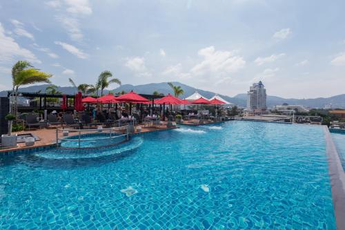 a large swimming pool with red umbrellas in a resort at The Charm Resort Phuket in Patong Beach
