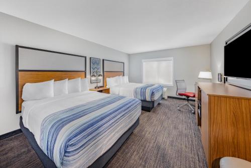 a hotel room with two beds and a flat screen tv at AmericInn by Wyndham International Falls in International Falls
