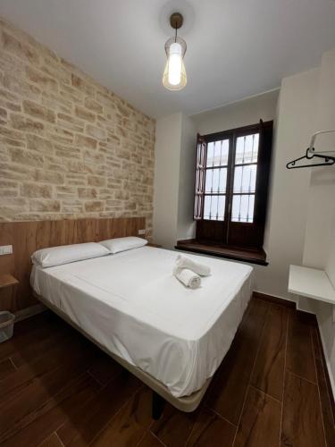 a bed in a room with a brick wall at Apartamentos Rey in Córdoba