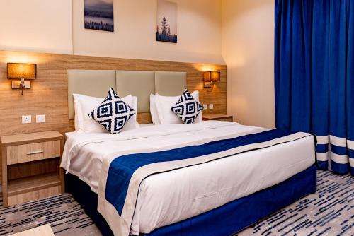 a bedroom with a large bed with blue curtains at idles By Staytion Serviced Apartments in Jeddah