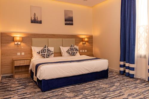 a bedroom with a large bed with blue curtains at idles By Staytion Serviced Apartments in Jeddah