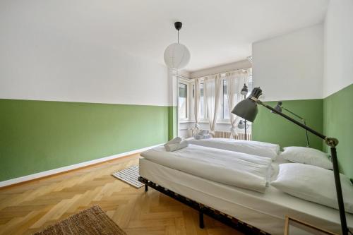 - une chambre avec un lit et un mur vert dans l'établissement Central Apartment for City Explorers 224, à Zurich