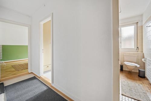 La salle de bains est pourvue d'un mur blanc et de toilettes. dans l'établissement Central Apartment for City Explorers 224, à Zurich