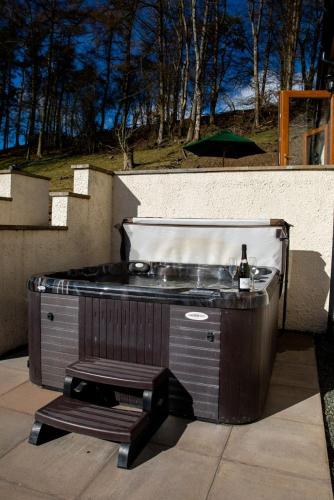 a barbecue grill on a patio with a bottle of wine at Pentre Fach in Llanddewi Ystradenny