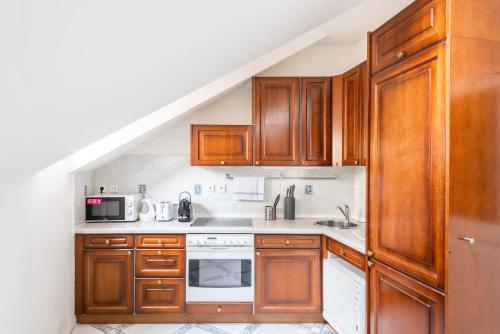 a kitchen with wooden cabinets and a microwave at St. George Apartments in Prague