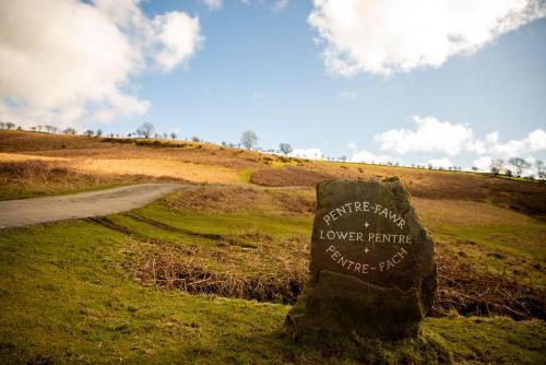a sign on top of a grassy hill with a road at Pentre Fawr in Llanddewi Ystradenny