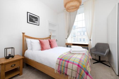um quarto com uma cama, uma cadeira e uma janela em JOIVY Bright 2 bed flat, sleeps 6, next to Holyrood Park em Edinburgo