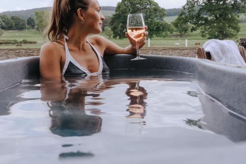 雷雅特的住宿－The Hafod，坐在热水浴缸中的女人,喝一杯葡萄酒