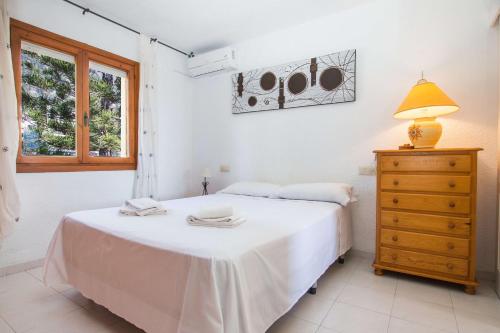 1 dormitorio con 1 cama blanca, cómoda y lámpara en Villa Erik - PlusHolidays, en Calpe