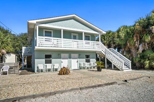 a house with a white deck and chairs and palm trees at Adorable Beach Cottages by Panhandle Getaways in Gulf Resort Beach