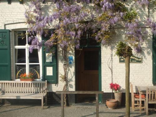 ein Gebäude mit einer Bank und einem Baum mit lila Blumen in der Unterkunft Hotel In't Boldershof in Deurle