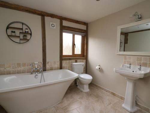 a bathroom with a tub and a toilet and a sink at The Hayloft in Knighton