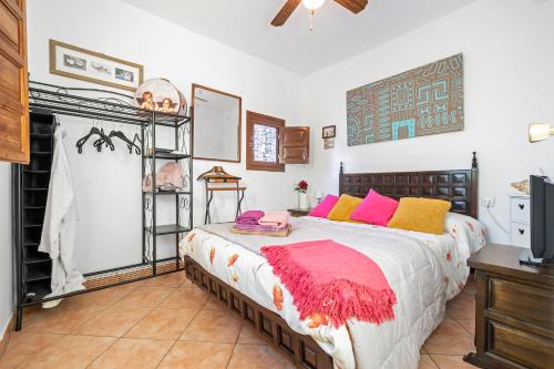 a bedroom with a bed with pink and yellow pillows at Abeles' home Villa de Alquiler in Masllorens