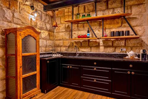 cocina con armarios negros y pared de piedra en snowflake.golan, en Majdal Shams