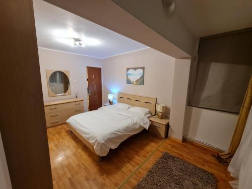 a bedroom with a white bed and a television at Apartament Avram in Petroşani