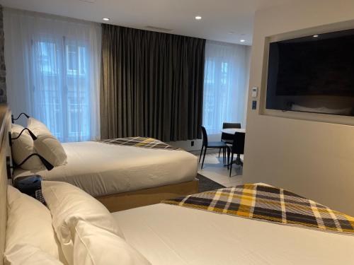 a hotel room with two beds and a flat screen tv at Hotel du Vieux Quebec in Quebec City