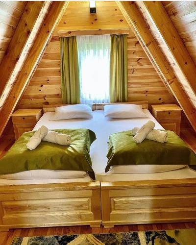 a bedroom with two beds in a log cabin at Apartmani i kuće Moje selo Šćepanović in Kolašin