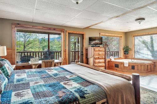 um quarto com uma cama, uma banheira e janelas em Alpine Rose Beautiful Cabin Hot Tub Mountain Views em Sevierville