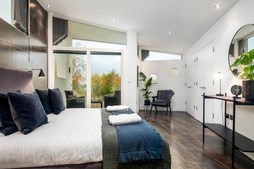 een slaapkamer met een groot bed en een groot raam bij Lakeside property with spa access on a nature reserve Reid Villa CW01 in Somerford Keynes