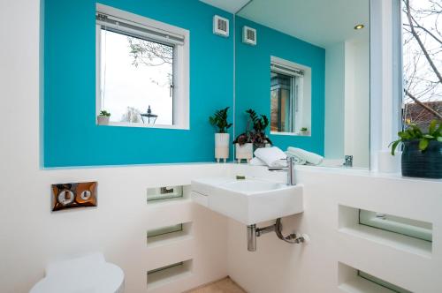 een badkamer met een witte wastafel en een blauwe muur bij Lakeside property with spa access on a nature reserve Reid Villa CW01 in Somerford Keynes