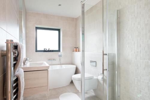 a bathroom with a tub and a toilet and a sink at Luxury property with access into Spa on a nature reserve Beaumont Village 14 in Warmwell