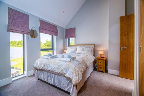 um quarto com uma cama e uma grande janela em Luxury property with access into Spa on a nature reserve Beaumont Village 5 BV05 em Warmwell