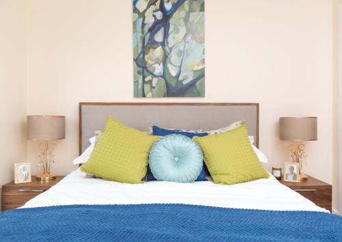 1 dormitorio con 1 cama con almohadas amarillas y azules en Lakeside property with spa access on a nature reserve Rainbows BV17, en Warmwell