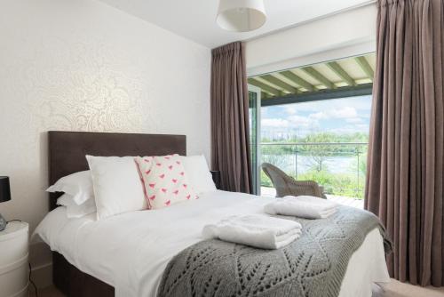 Somerford KeynesにあるLakeside property with spa access on a nature reserve Pochard HM109のベッドと大きな窓のある寝室