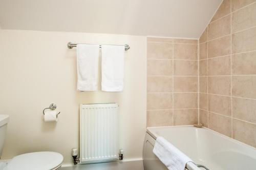 ein Badezimmer mit einer Badewanne, einem WC und einem Waschbecken in der Unterkunft Lakeside property with access into Spa on a nature reserve Bee Cottage HM75 in Somerford Keynes