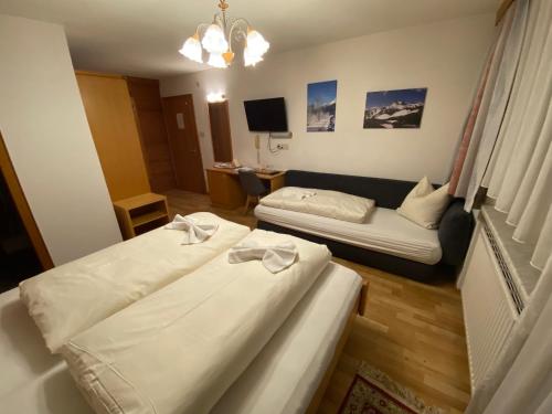 a hotel room with two beds and a couch at Appartement Pension St. Sebastian in Pettneu am Arlberg