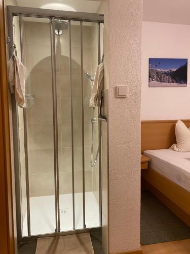 a glass shower in a room with a bed at Appartement Pension St. Sebastian in Pettneu am Arlberg