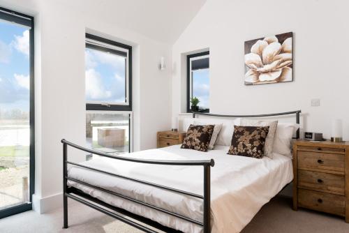 een slaapkamer met een bed en 2 ramen bij Lakeside property with spa access on a nature reserve Sand Martin BV07 in Warmwell