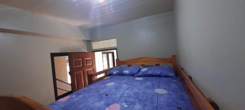 a bedroom with a bed with a blue comforter at The Pine Place - Baguio in Baguio