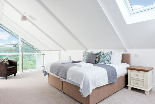 une chambre blanche avec un lit et une chaise dans l'établissement Lakeside property with spa access on a nature reserve Swans Rest HM103, à Somerford Keynes