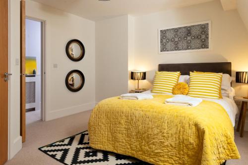 a bedroom with a large bed with yellow blankets and pillows at Penthouse apartment with a Spa on a nature reserve Willow Warbler HM112 in Somerford Keynes