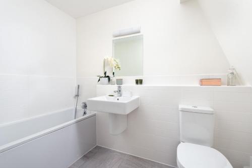 a white bathroom with a toilet and a sink at Penthouse apartment with a Spa on a nature reserve Willow Warbler HM112 in Somerford Keynes