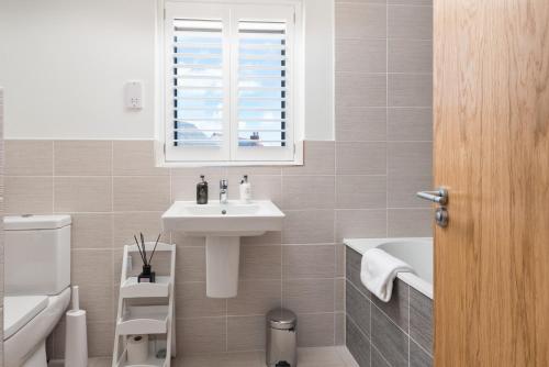 a white bathroom with a sink and a window at Lakeside property with spa access on a nature reserve Tally Ho BV19 in Warmwell