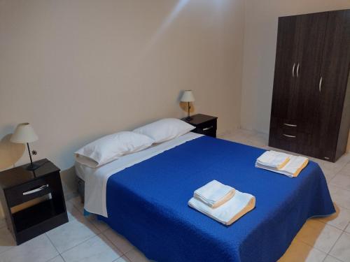 a bedroom with a blue bed with two towels on it at La Candida in Tunuyán